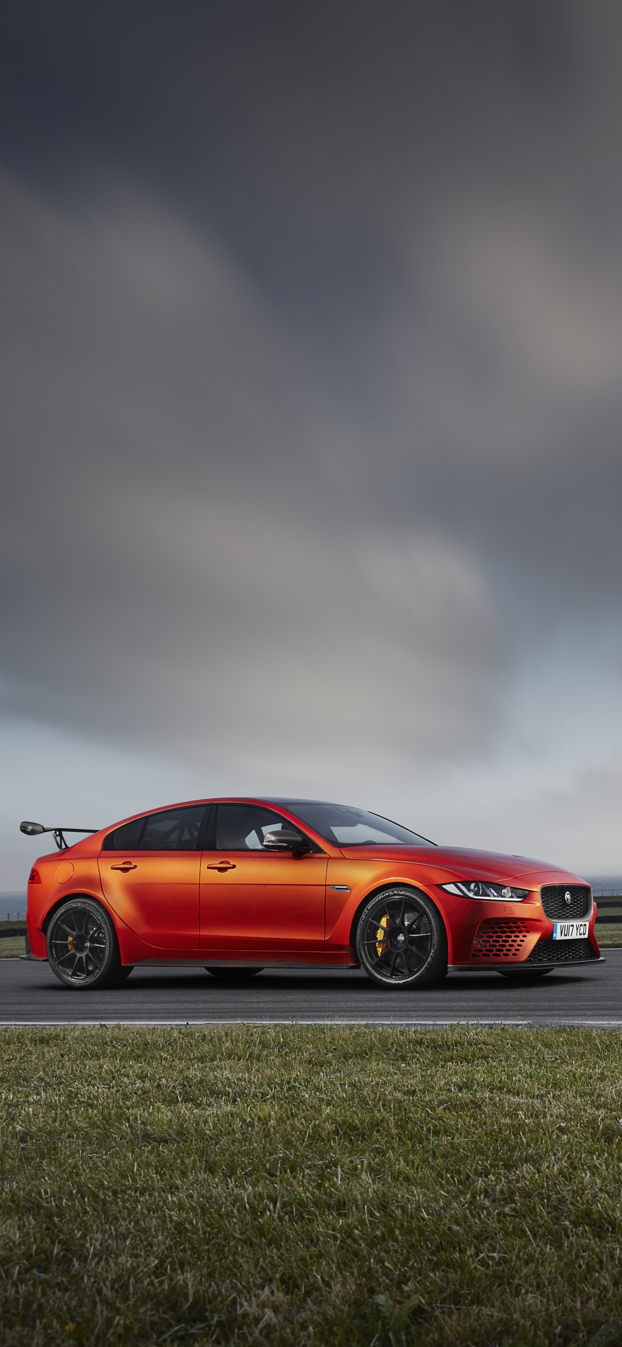 Rotes Coupe Auf Grauer Asphaltstraße Unter Grau Bewölktem Himmel. Wallpaper in 1242x2688 Resolution