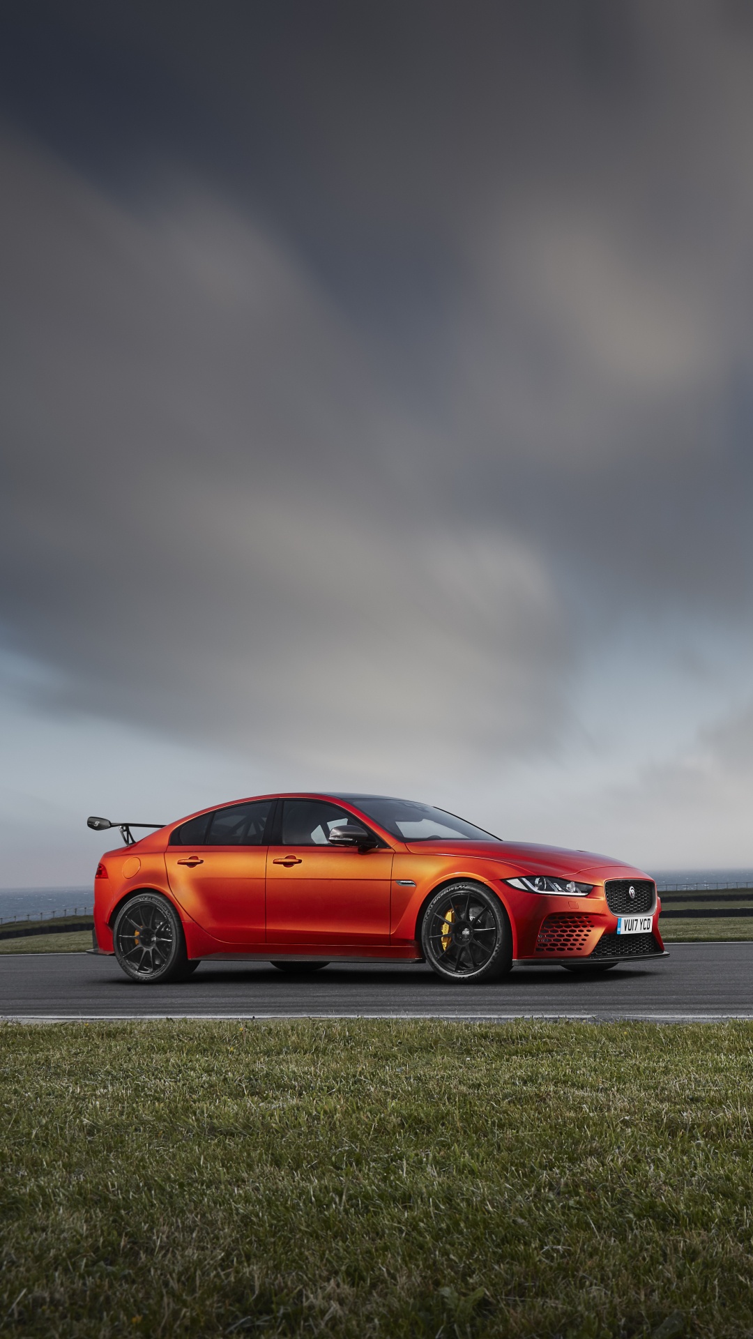 Red Coupe on Gray Asphalt Road Under Gray Cloudy Sky. Wallpaper in 1080x1920 Resolution
