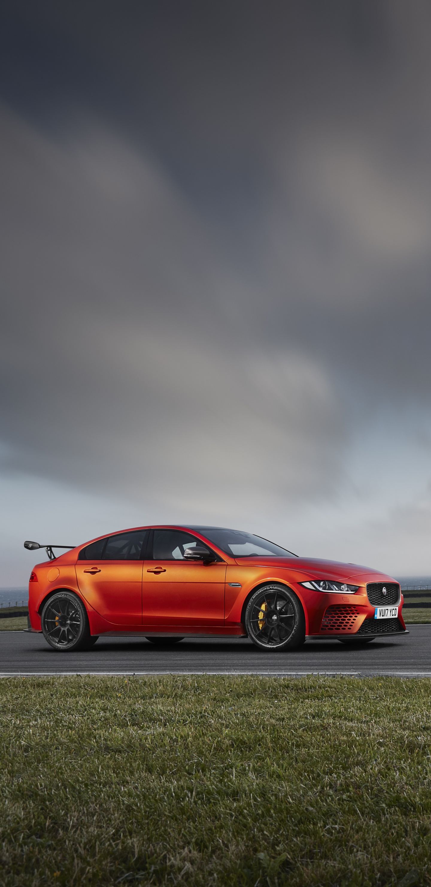 Red Coupe on Gray Asphalt Road Under Gray Cloudy Sky. Wallpaper in 1440x2960 Resolution
