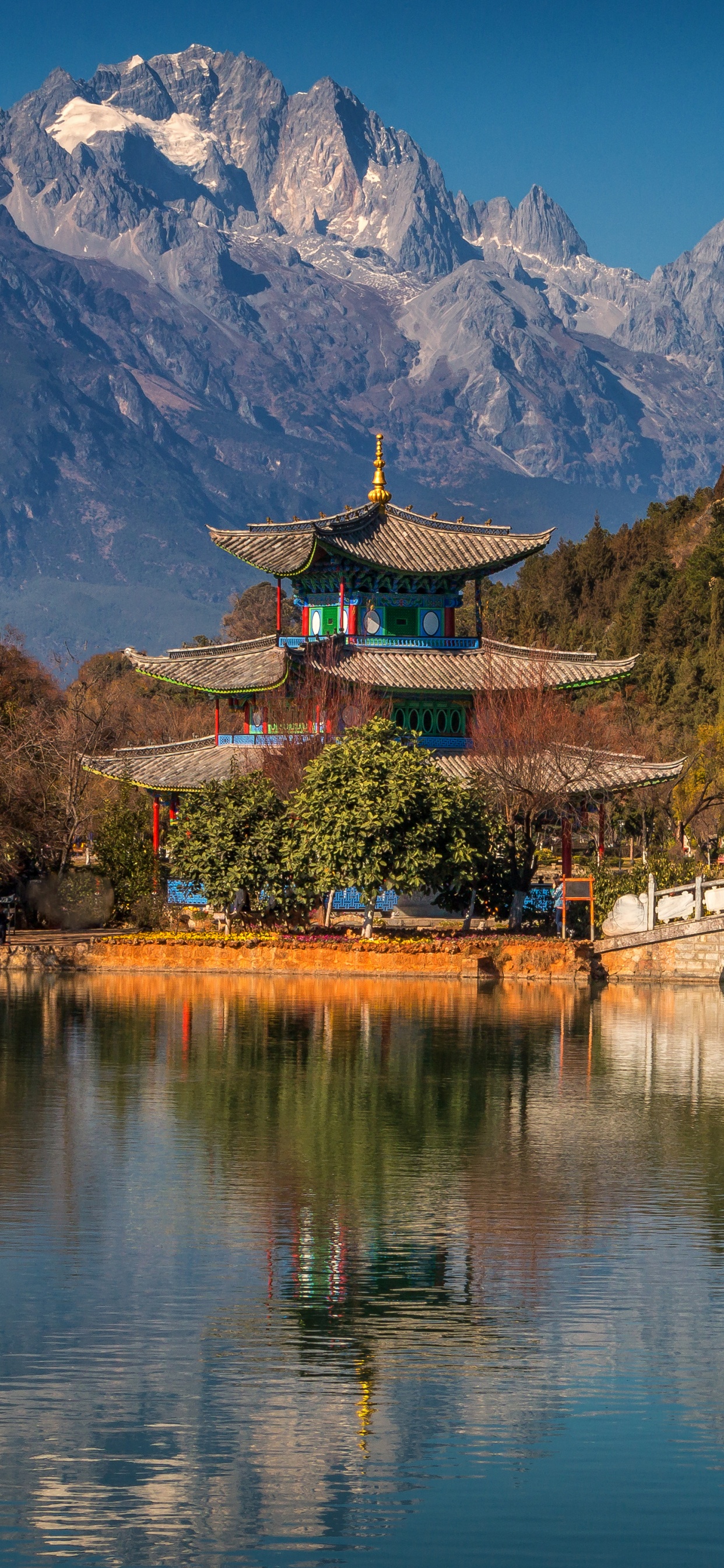 Brown Wooden Bridge Over River Near Mountain. Wallpaper in 1242x2688 Resolution