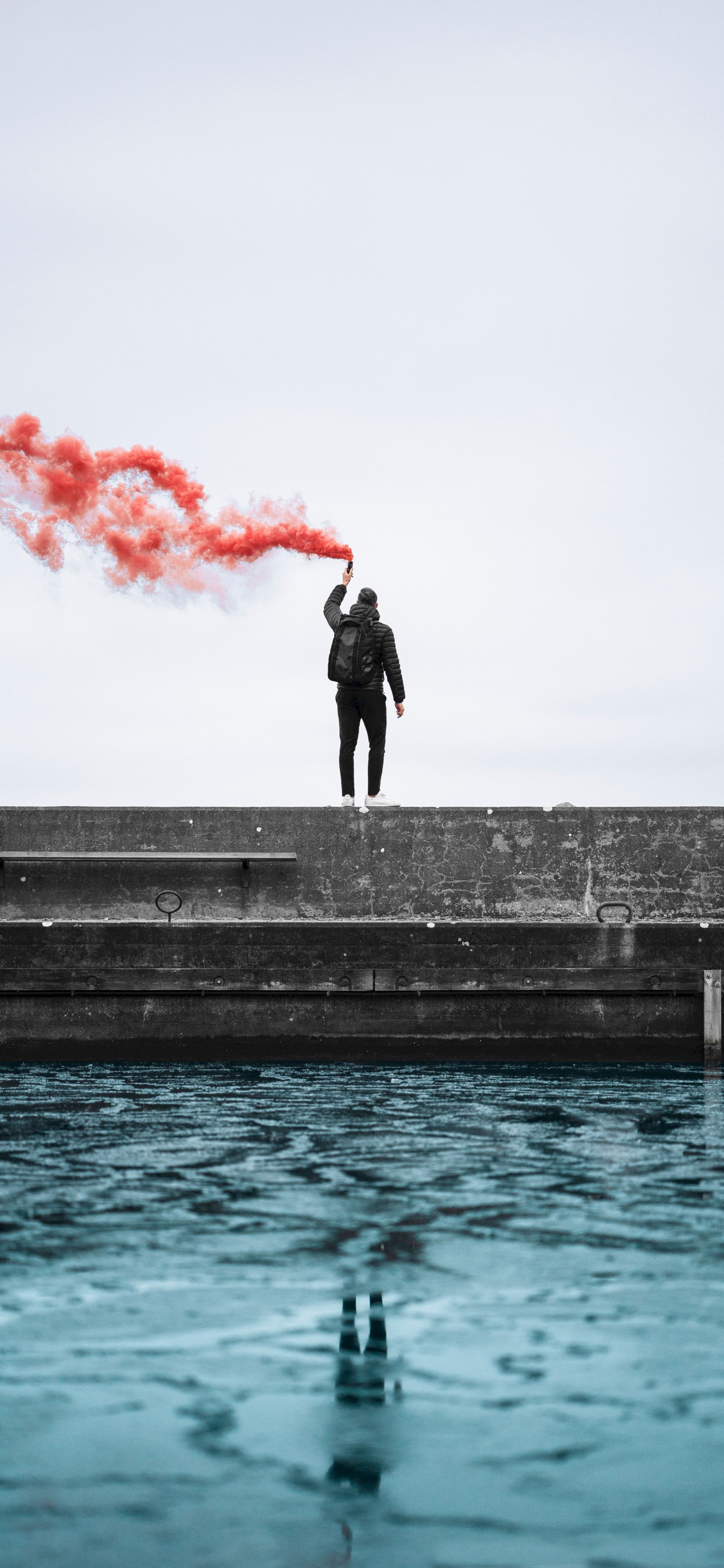 Man in Black Jacket Standing on Concrete Dock During Daytime. Wallpaper in 1242x2688 Resolution