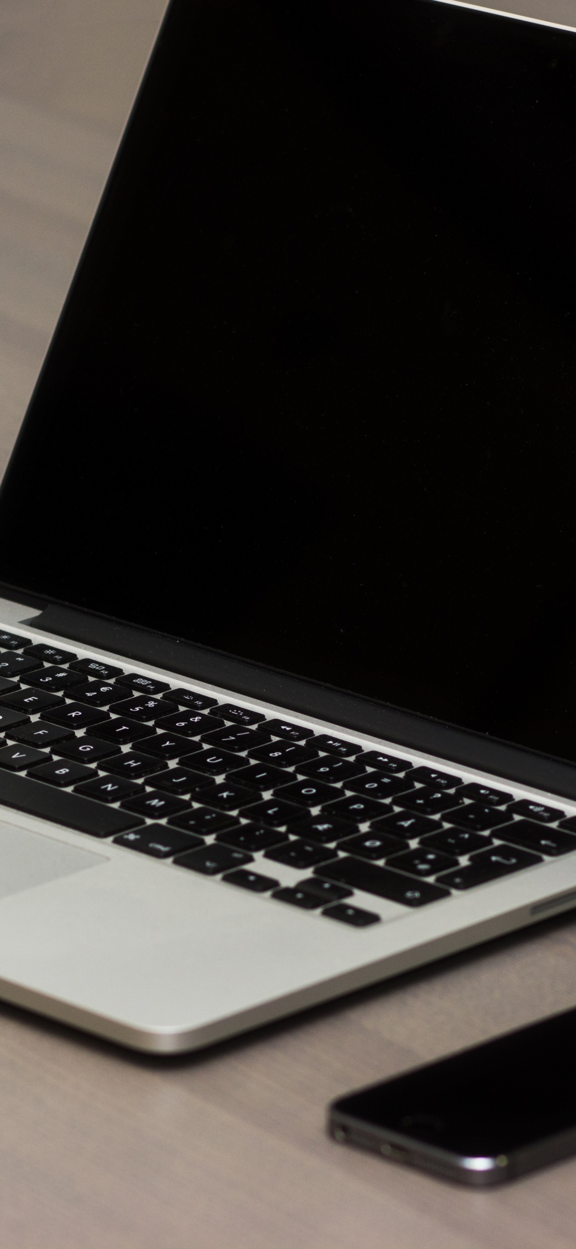 Macbook Pro Beside Black Smartphone on Brown Wooden Table. Wallpaper in 1125x2436 Resolution