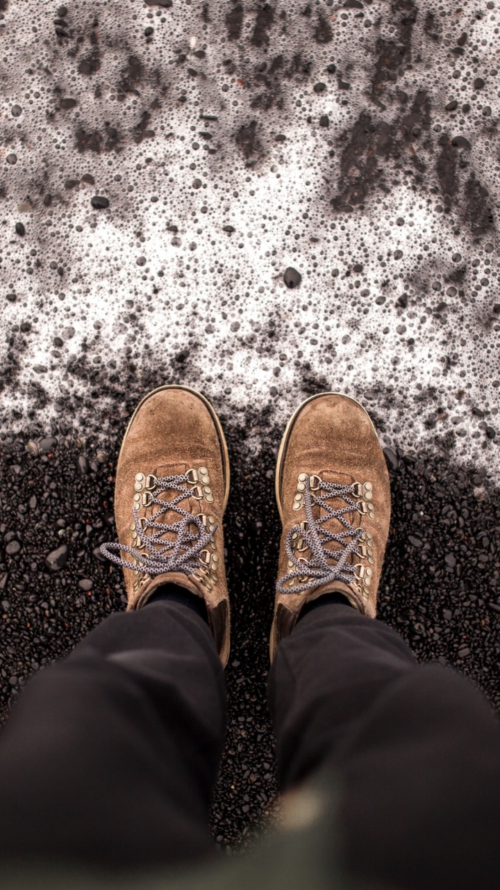Person in Black Pants and Brown Shoes Standing on Snow Covered Ground. Wallpaper in 720x1280 Resolution