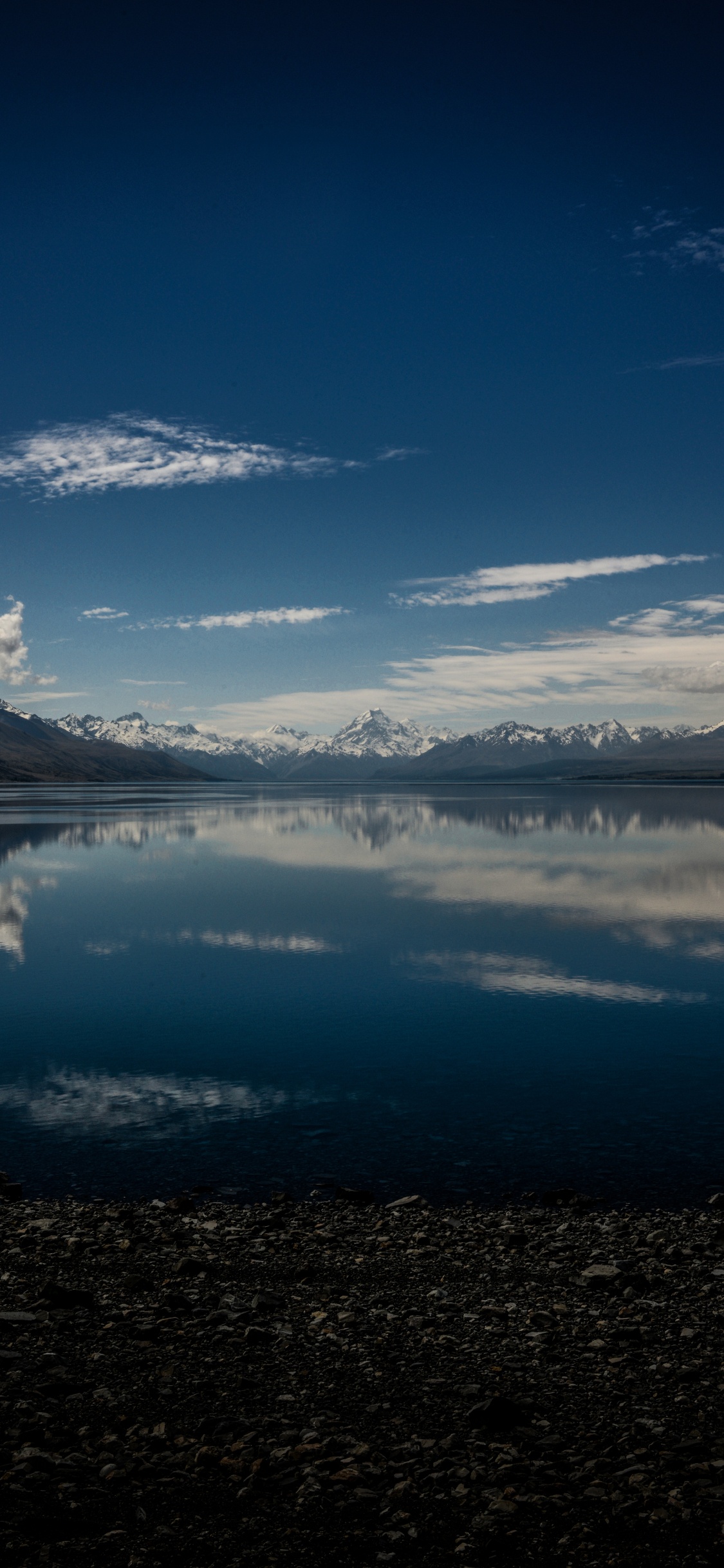 Cuerpo de Agua Cerca de la Montaña Bajo un Cielo Azul Durante el Día. Wallpaper in 1125x2436 Resolution