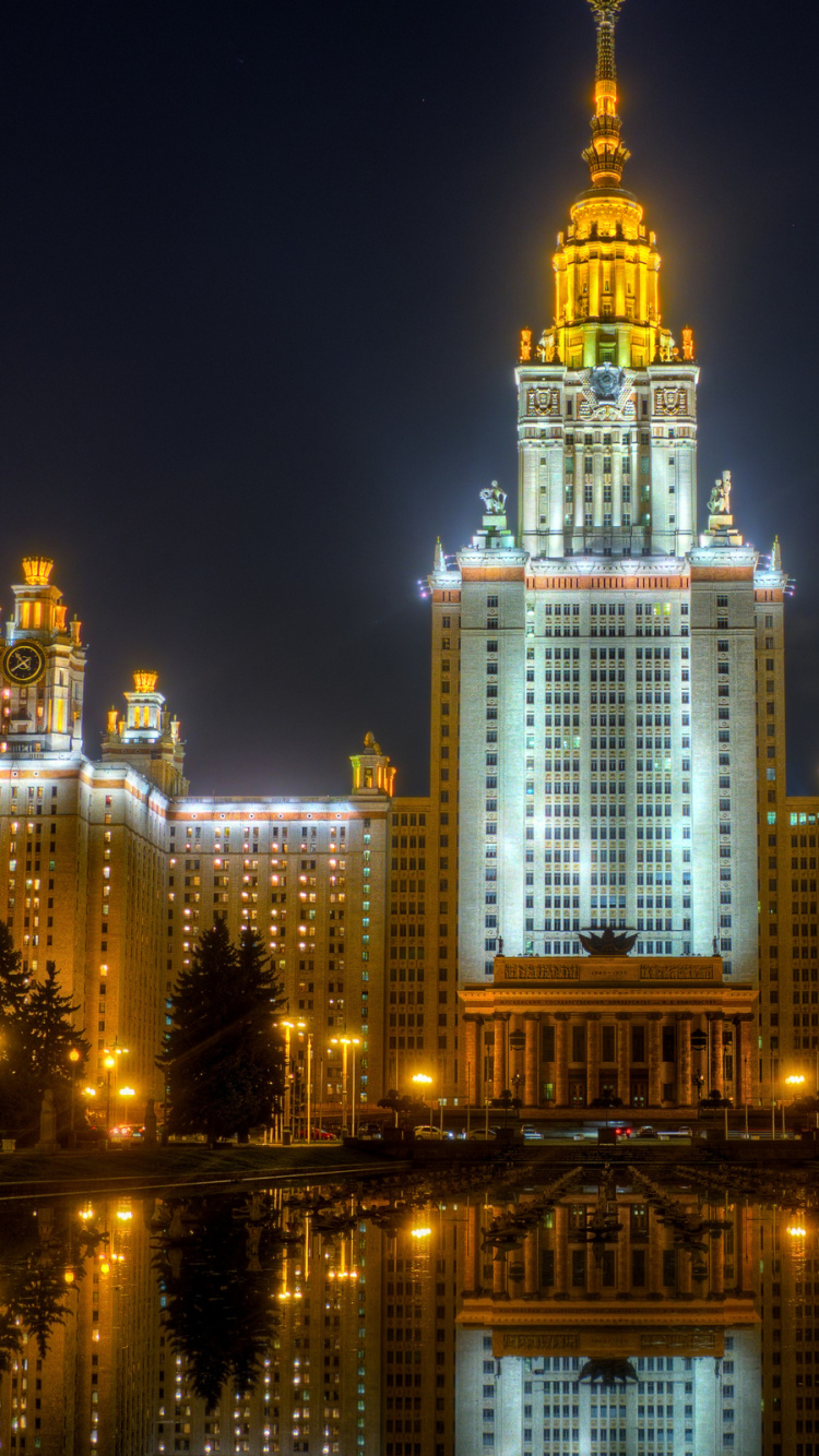 White and Blue Lighted Building Near Body of Water During Night Time. Wallpaper in 750x1334 Resolution