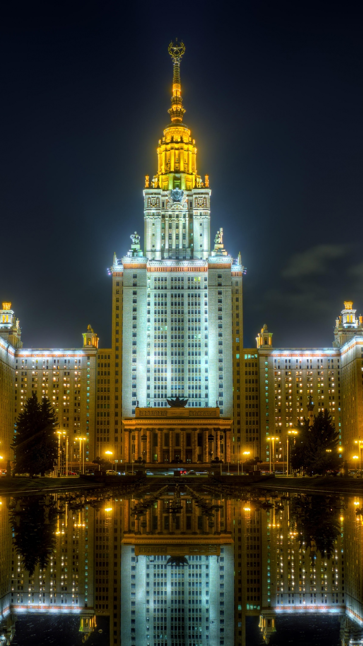 Edificio Iluminado Cerca Del Cuerpo de Agua Durante la Noche.. Wallpaper in 1440x2560 Resolution