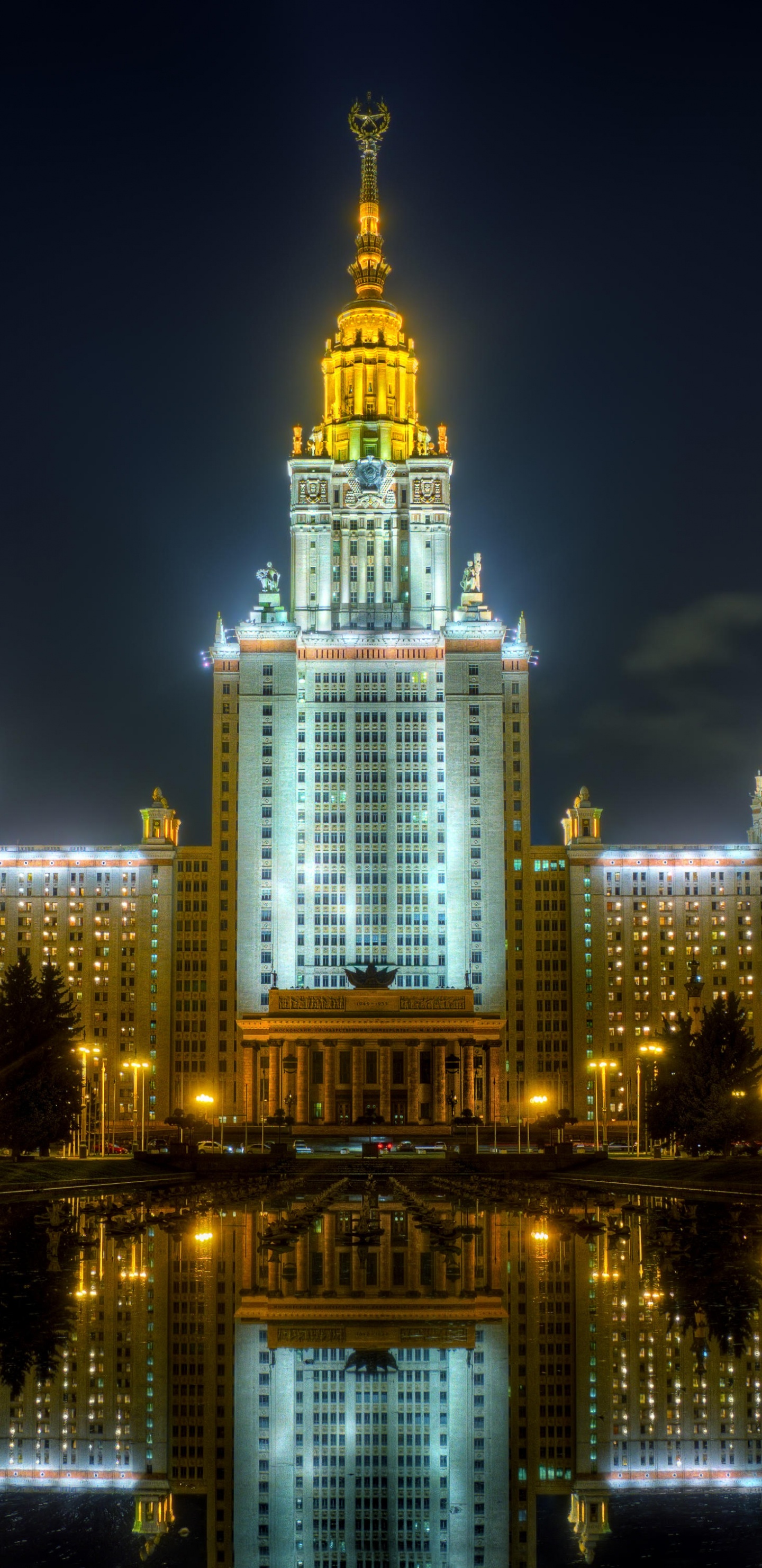 Edificio Iluminado Cerca Del Cuerpo de Agua Durante la Noche.. Wallpaper in 1440x2960 Resolution