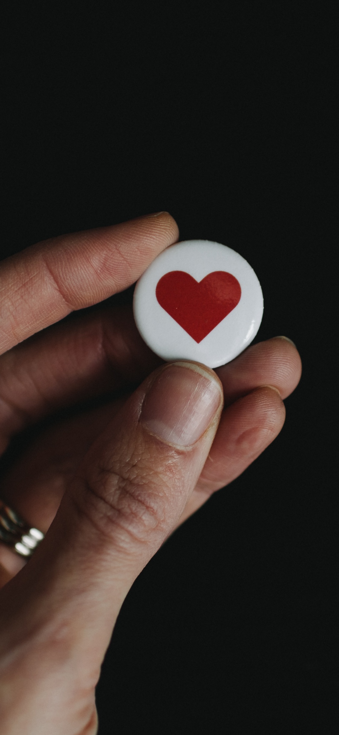 Person Holding White and Red Heart Shape Ornament. Wallpaper in 1125x2436 Resolution