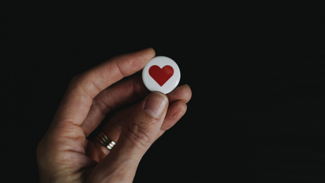 Person Holding White and Red Heart Shape Ornament. Wallpaper in 1280x720 Resolution