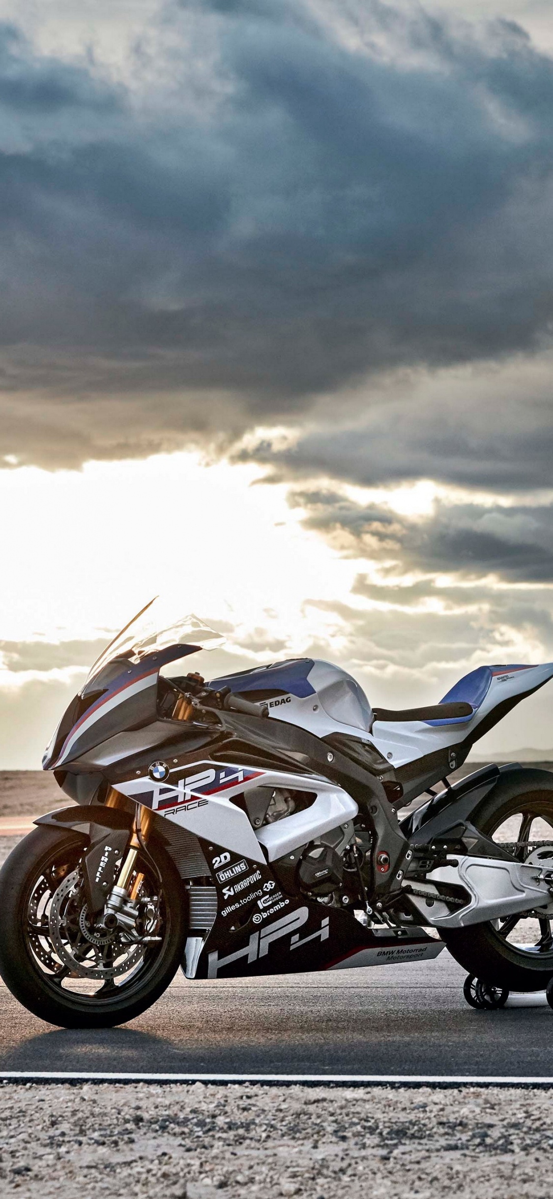 Moto Noir et Argent Sur Route Asphaltée Grise Sous Des Nuages Blancs Pendant la Journée. Wallpaper in 1125x2436 Resolution