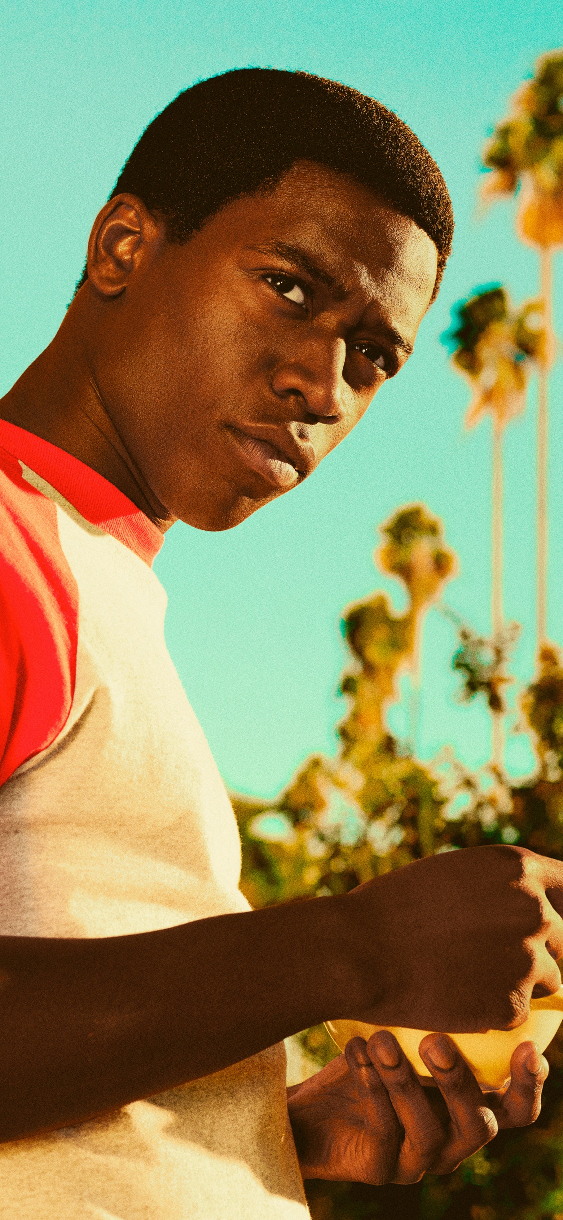 Man in White and Red Crew Neck T-shirt Standing Near Yellow Concrete Building During Daytime. Wallpaper in 1125x2436 Resolution