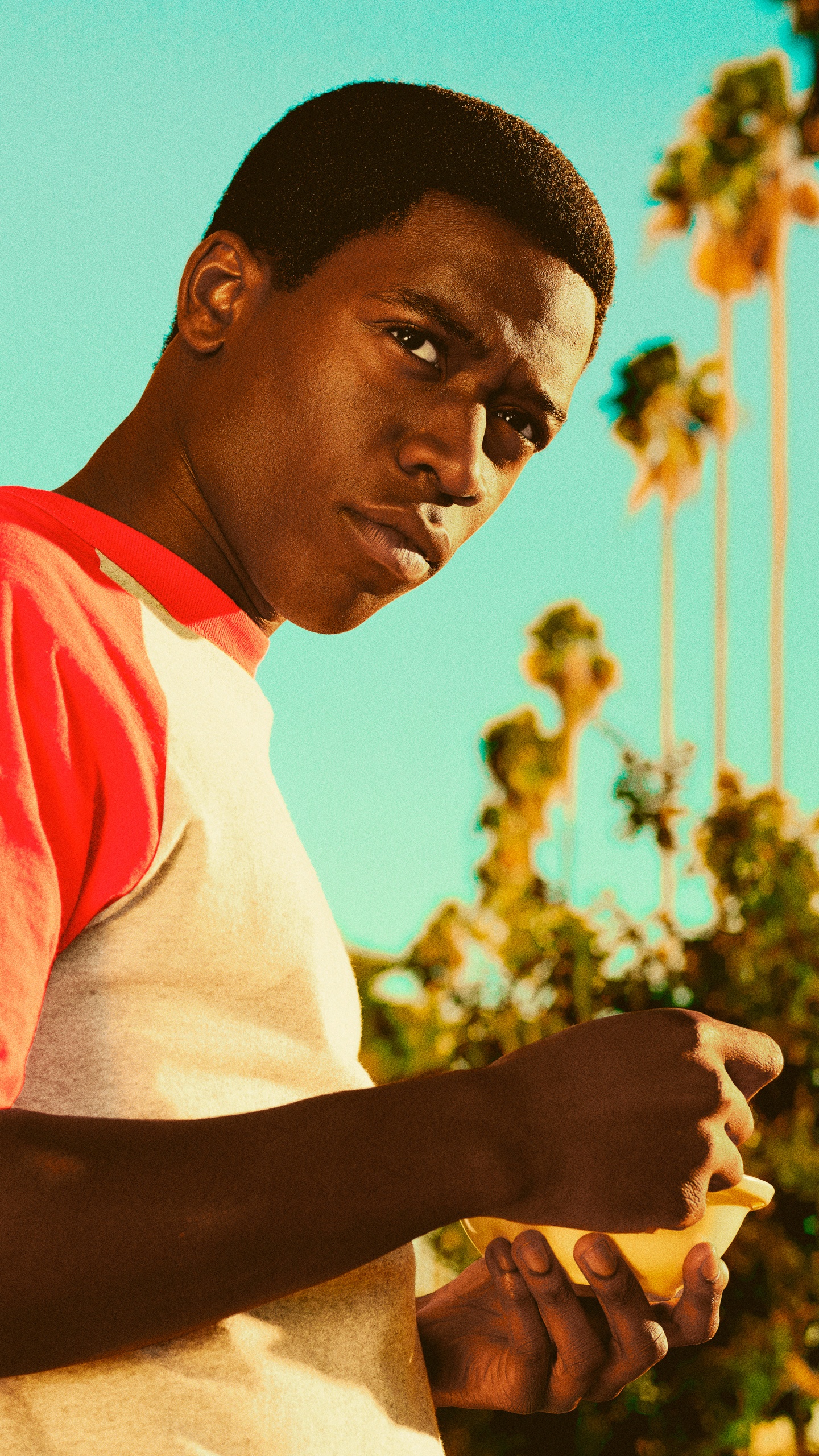 Man in White and Red Crew Neck T-shirt Standing Near Yellow Concrete Building During Daytime. Wallpaper in 1440x2560 Resolution