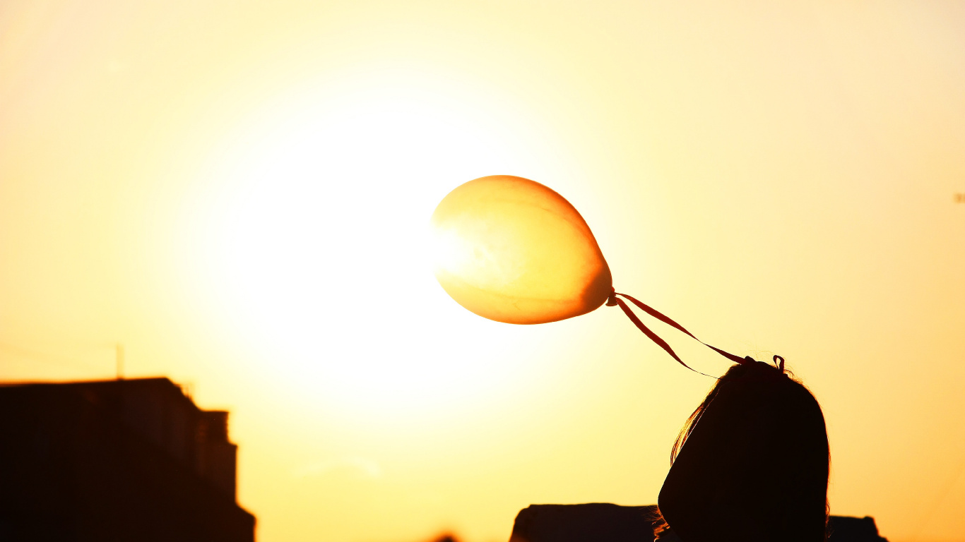 Silhouette of Man Holding Balloons During Sunset. Wallpaper in 1366x768 Resolution