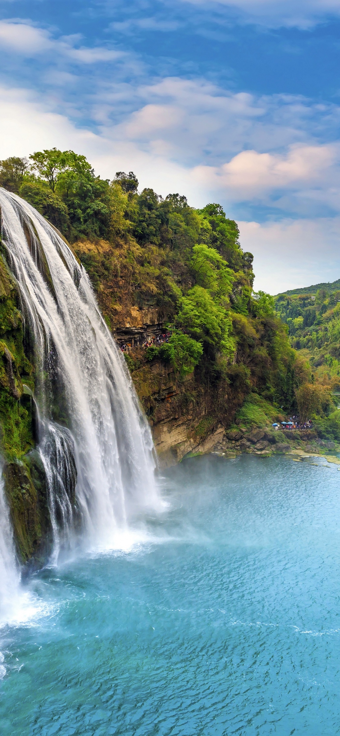 Waterfalls on Green Grass Covered Mountain During Daytime. Wallpaper in 1125x2436 Resolution