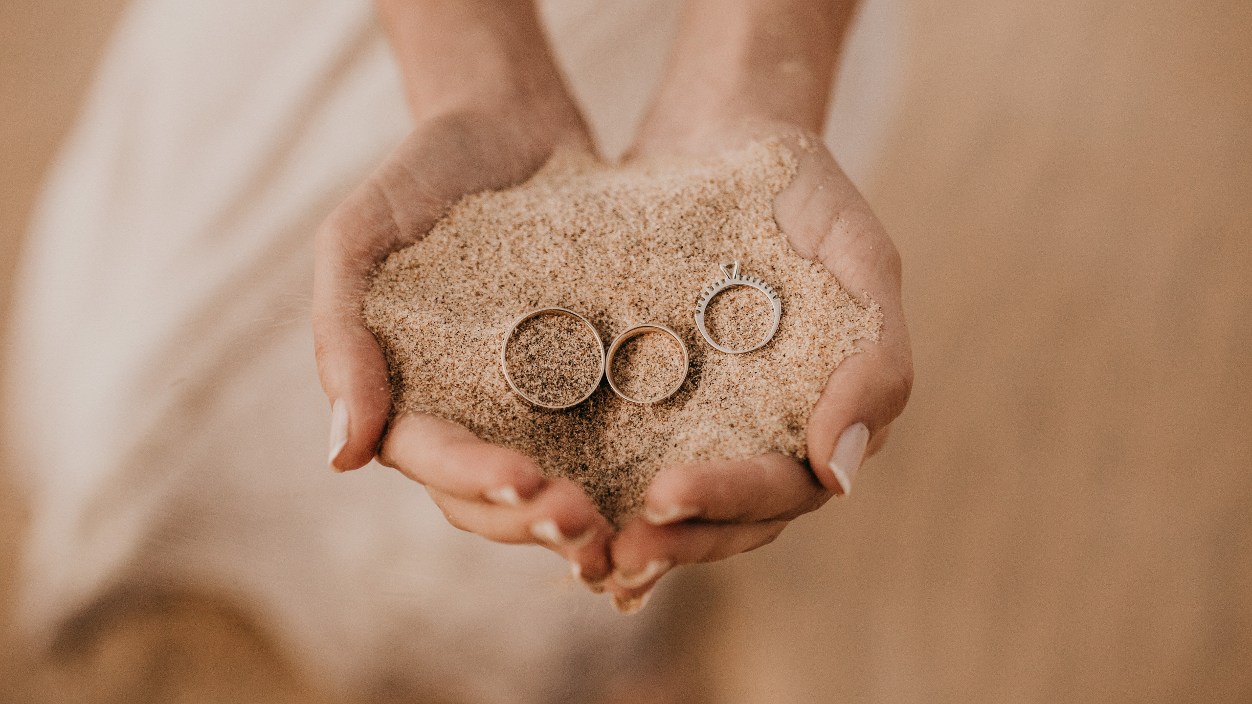 Person Holding Brown Sand on Top of White Textile. Wallpaper in 2560x1440 Resolution