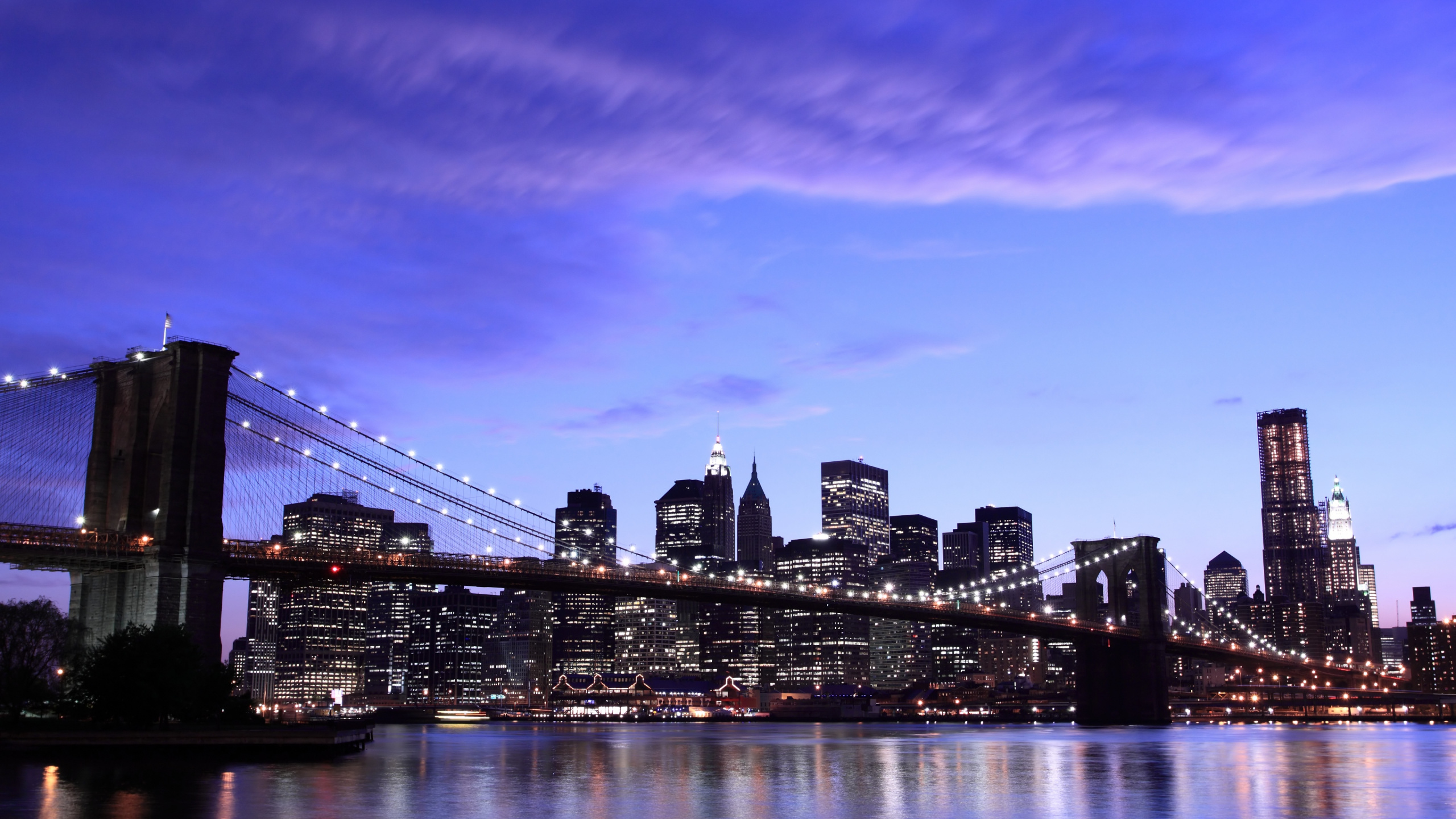 Skyline Der Stadt Über Gewässer Während Der Nacht. Wallpaper in 2560x1440 Resolution