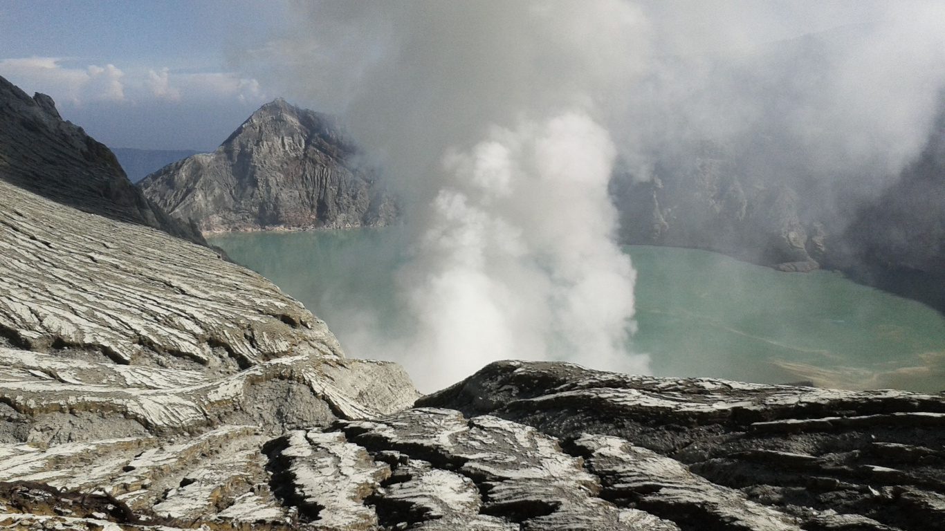 Brown Rocky Mountain Near Body of Water During Daytime. Wallpaper in 1366x768 Resolution