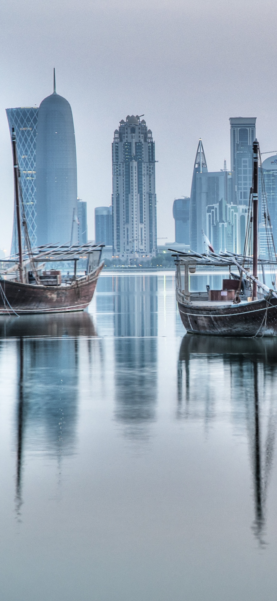 Weißes Und Blaues Boot Auf Dem Wasser in Der Nähe Von Stadtgebäuden Tagsüber. Wallpaper in 1125x2436 Resolution
