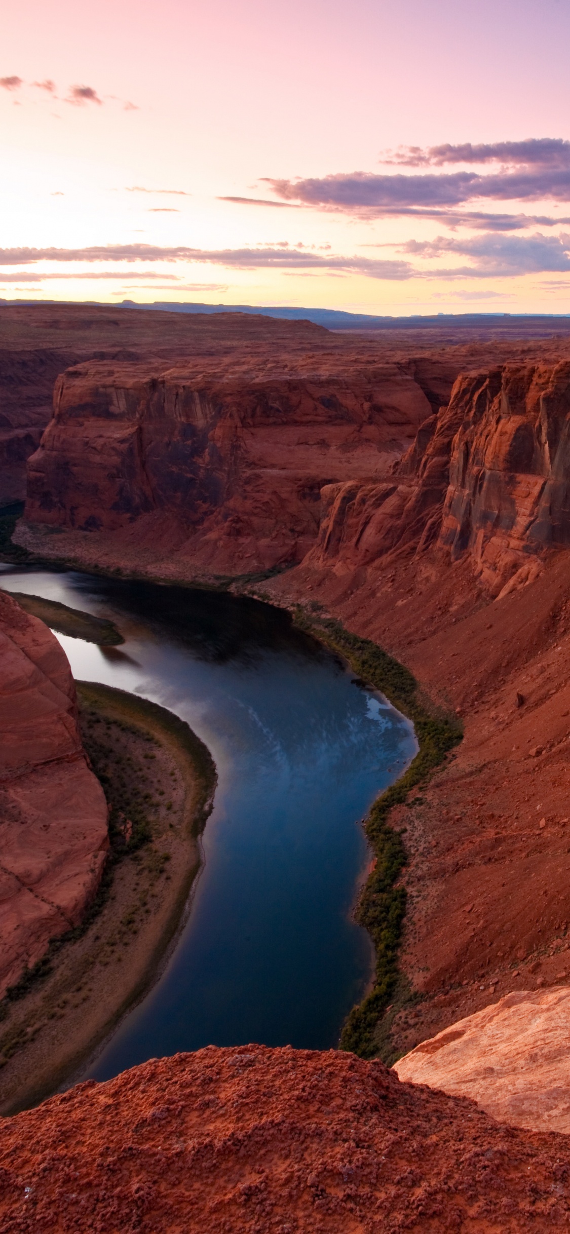 Formación de Roca Marrón Cerca Del Lago Azul Bajo un Cielo Azul Durante el Día. Wallpaper in 1125x2436 Resolution
