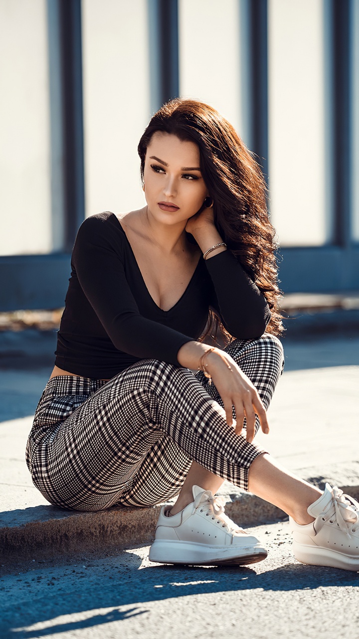 Woman in Black Long Sleeve Shirt and Black and White Striped Skirt Sitting on Concrete Floor. Wallpaper in 720x1280 Resolution