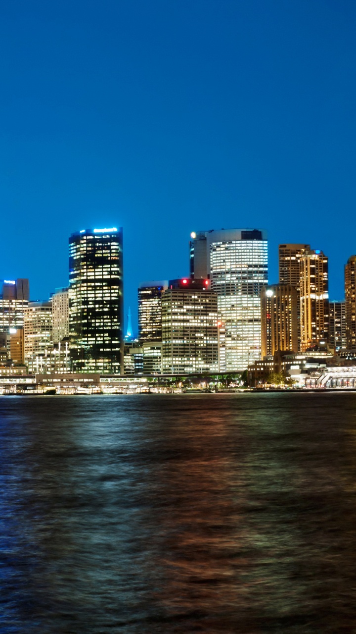 City Skyline Across Body of Water During Night Time. Wallpaper in 720x1280 Resolution