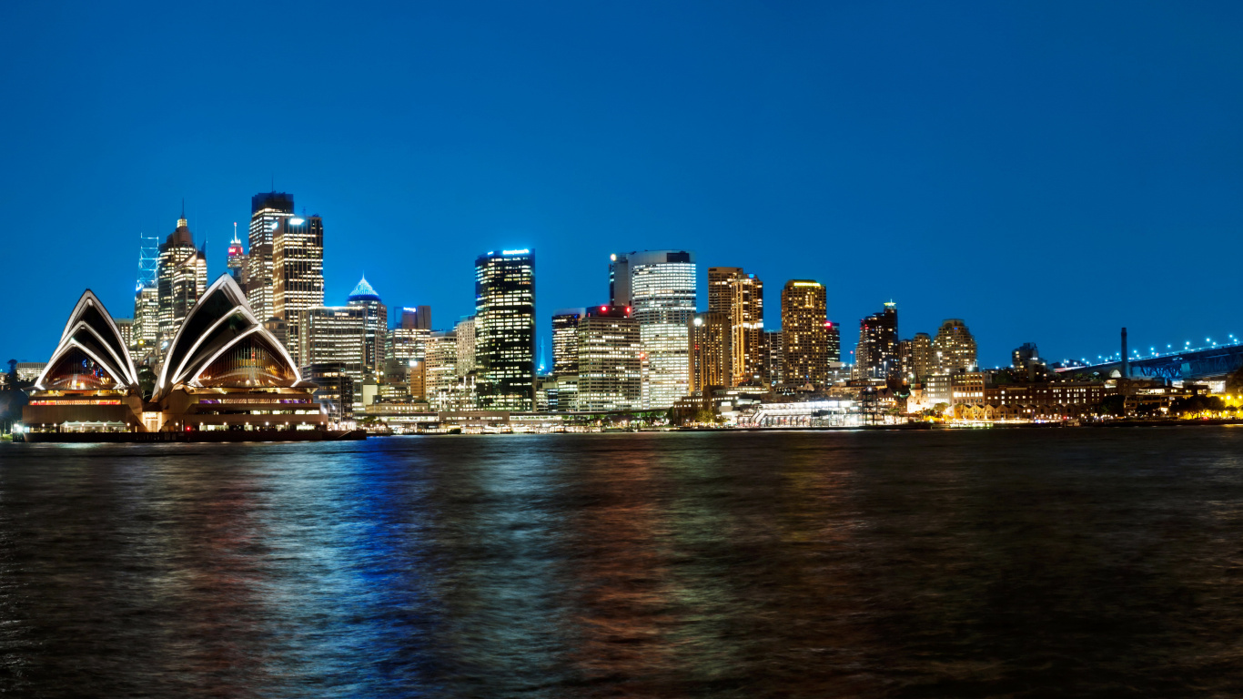 Skyline Der Stadt Über Gewässer Während Der Nacht. Wallpaper in 1366x768 Resolution