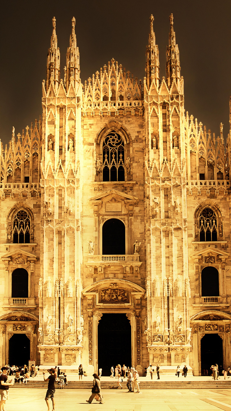 Gente Caminando Cerca Del Edificio de Hormigón Marrón Durante la Noche. Wallpaper in 750x1334 Resolution