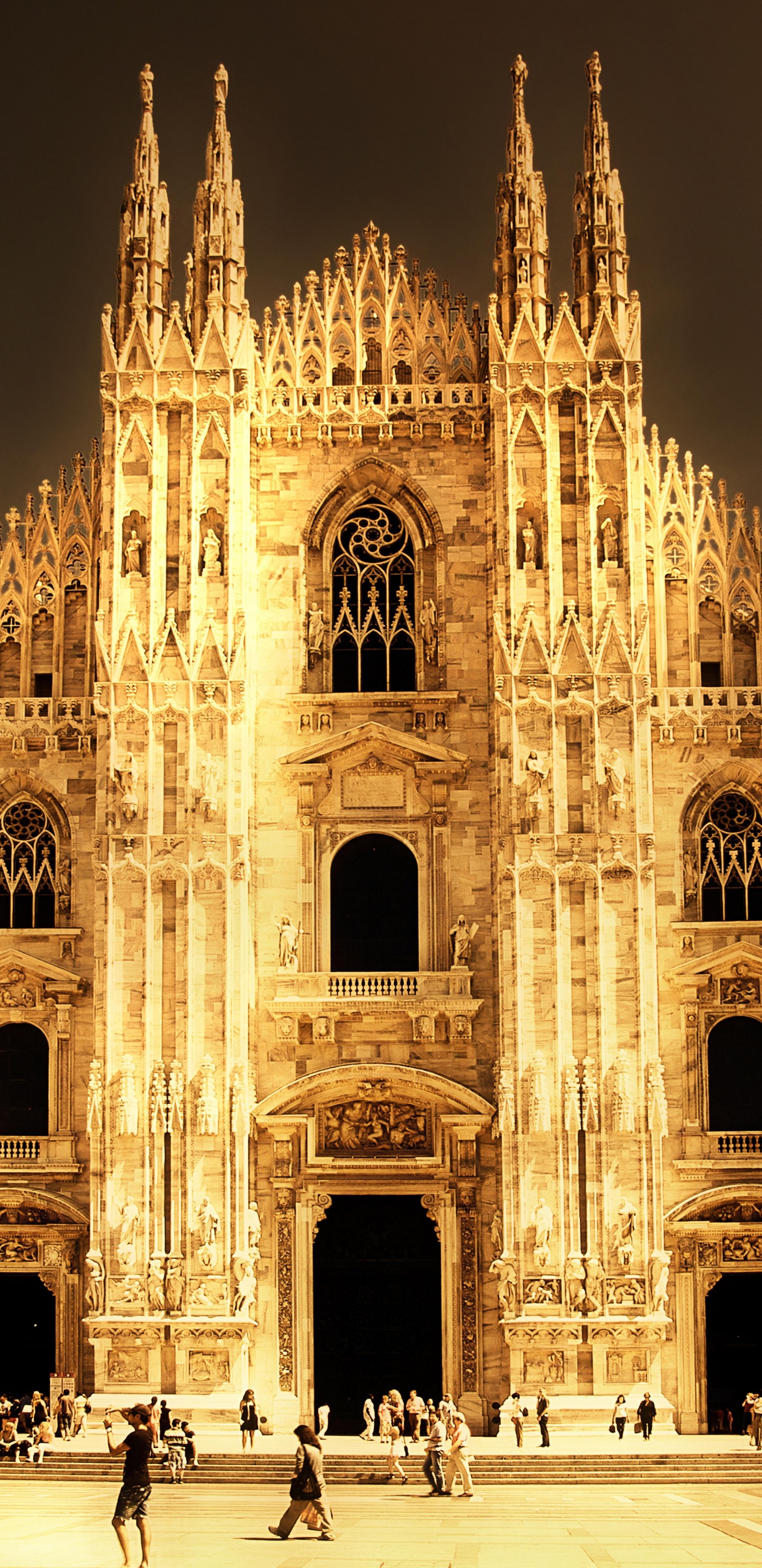 Personnes Marchant Près D'un Bâtiment en Béton Brun Pendant la Nuit. Wallpaper in 1440x2960 Resolution