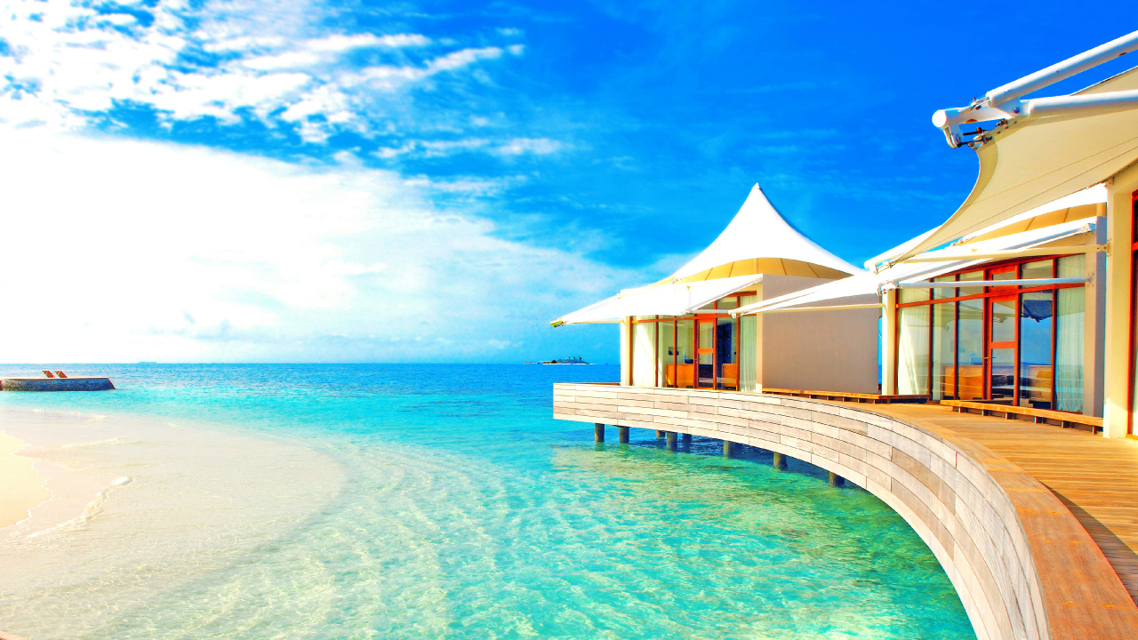 Maison de Plage en Bois Marron Sur Mer Bleue Sous Ciel Bleu Pendant la Journée. Wallpaper in 1280x720 Resolution