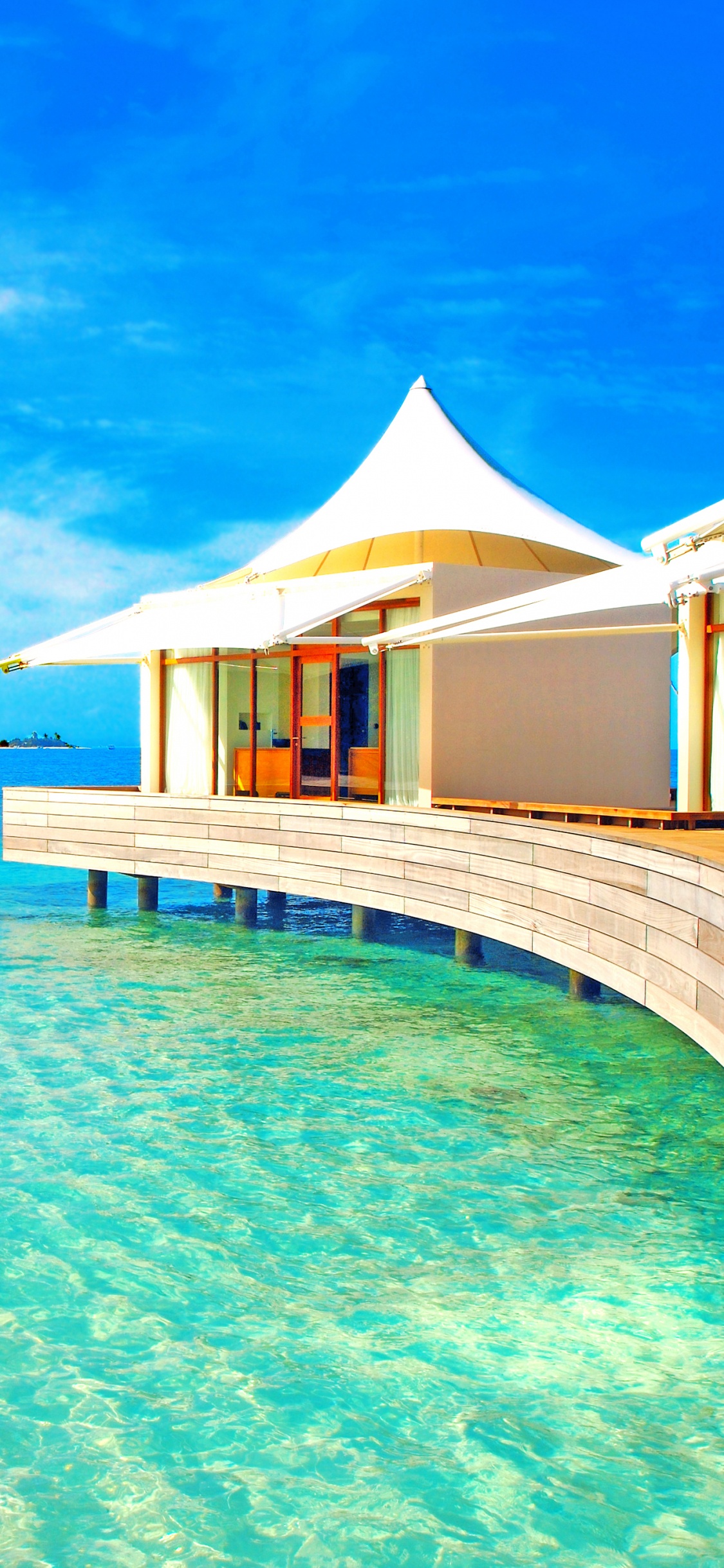 Brown Wooden Beach House on Blue Sea Under Blue Sky During Daytime. Wallpaper in 1125x2436 Resolution