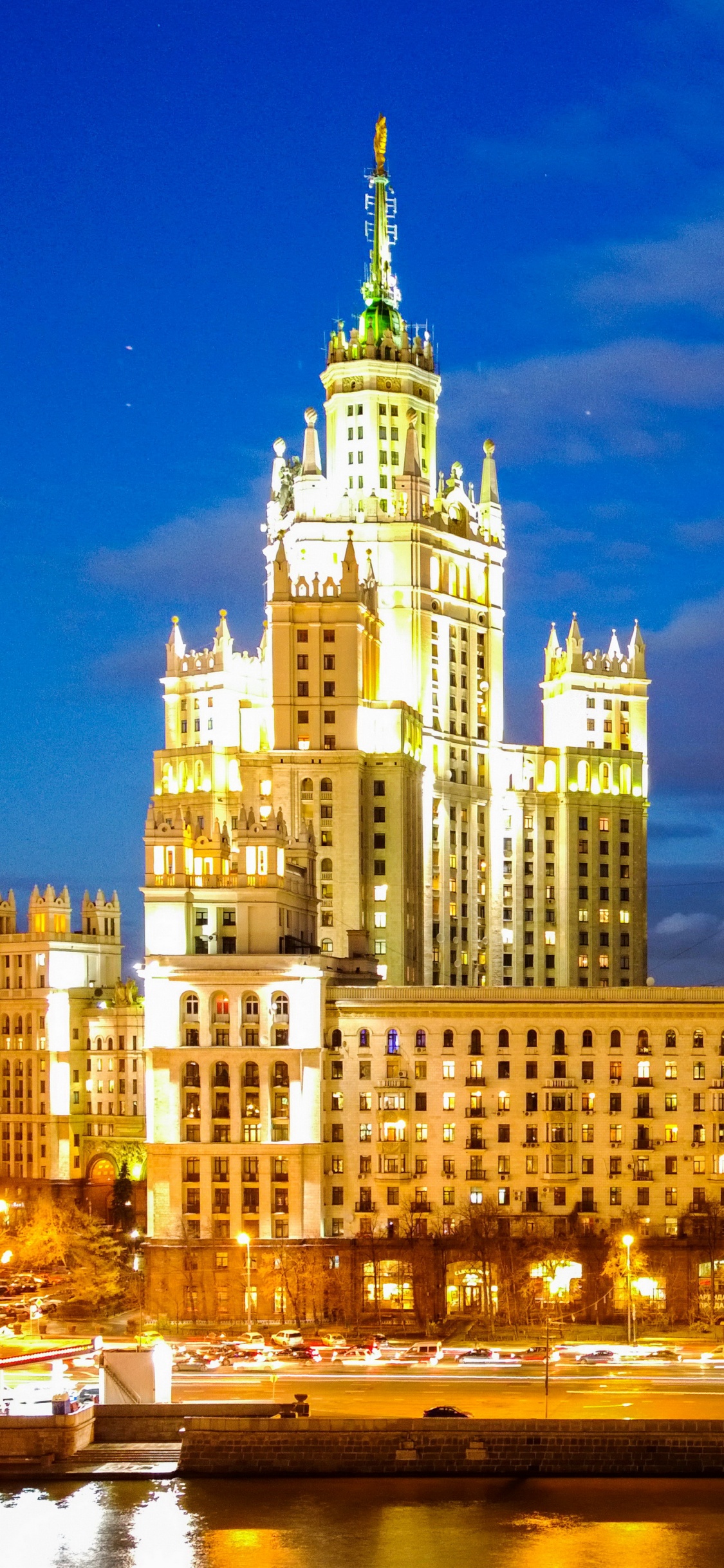 White Concrete Building Near Body of Water During Night Time. Wallpaper in 1125x2436 Resolution