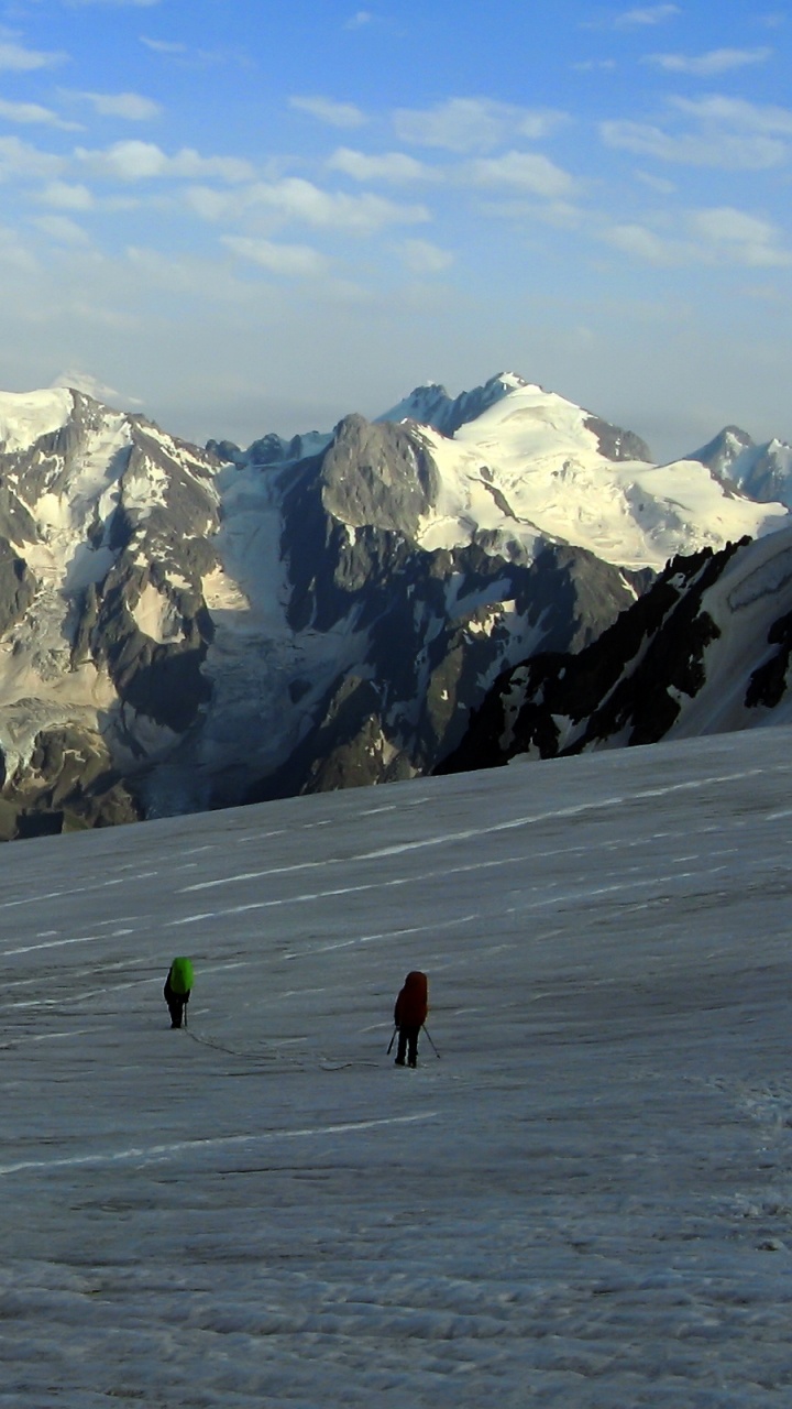 Personne en Veste Verte Marchant Sur un Champ Couvert de Neige Pendant la Journée. Wallpaper in 720x1280 Resolution