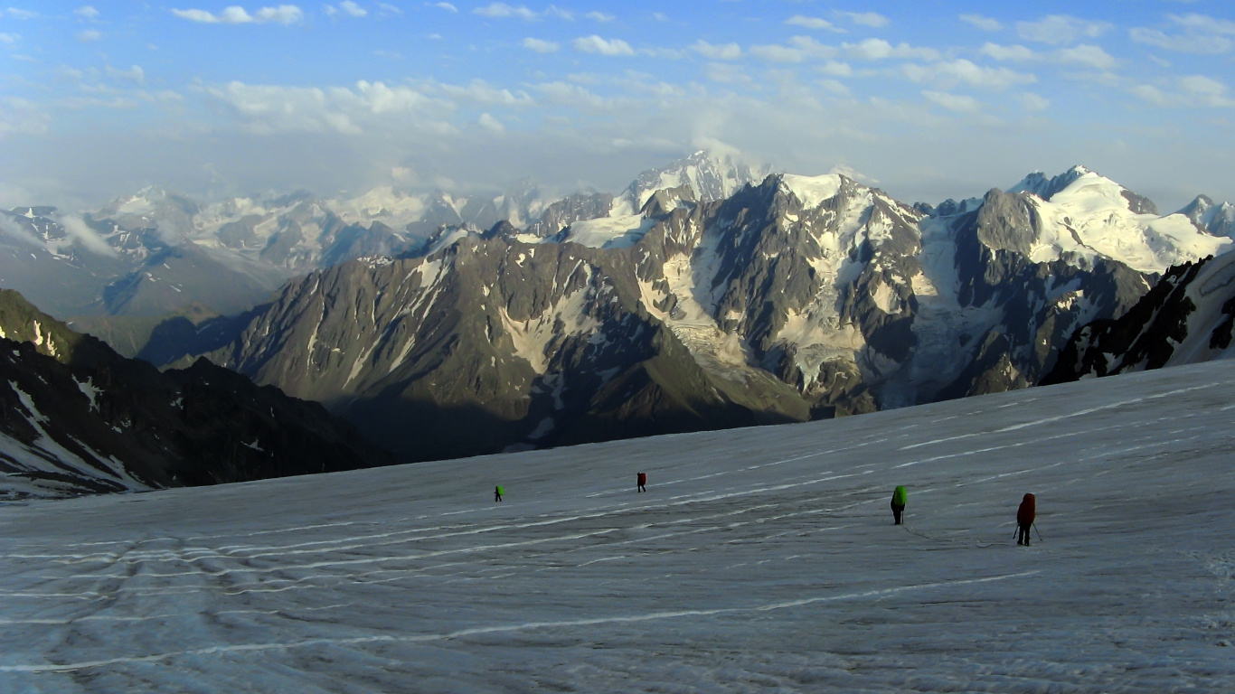 Person in Green Jacket Walking on Snow Covered Field During Daytime. Wallpaper in 1366x768 Resolution