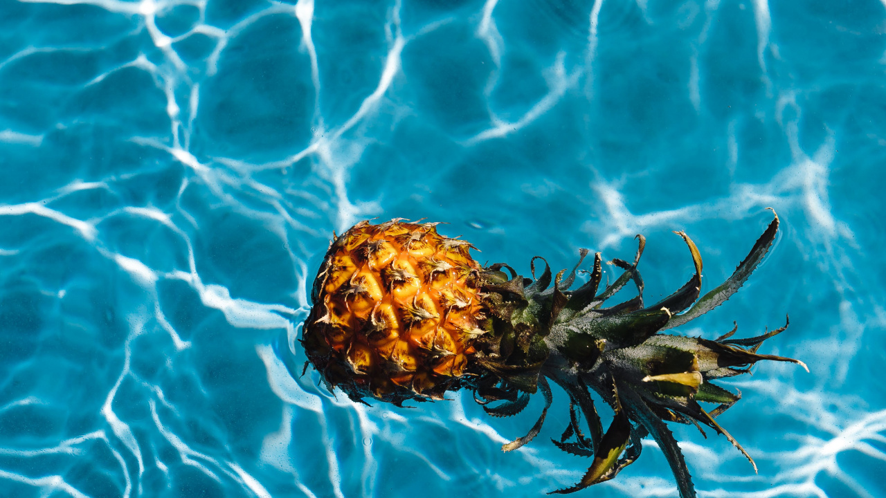 Brown and Green Pineapple Floating on Water. Wallpaper in 1280x720 Resolution