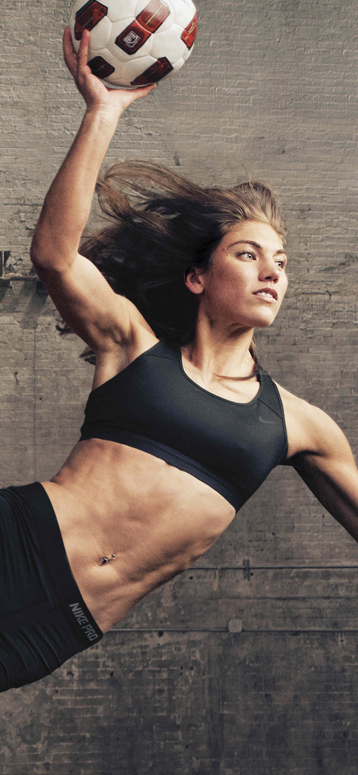 Frau in Schwarzem Sport-BH Und Schwarzen Shorts Mit Weißem Und Rotem Fußball. Wallpaper in 1242x2688 Resolution
