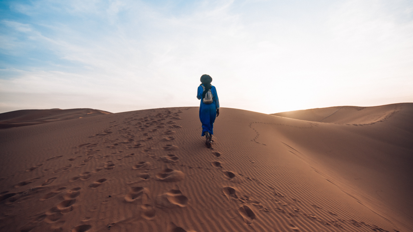 Personne en Veste Bleue Marchant Sur du Sable Brun Sous Ciel Bleu Pendant la Journée. Wallpaper in 1366x768 Resolution