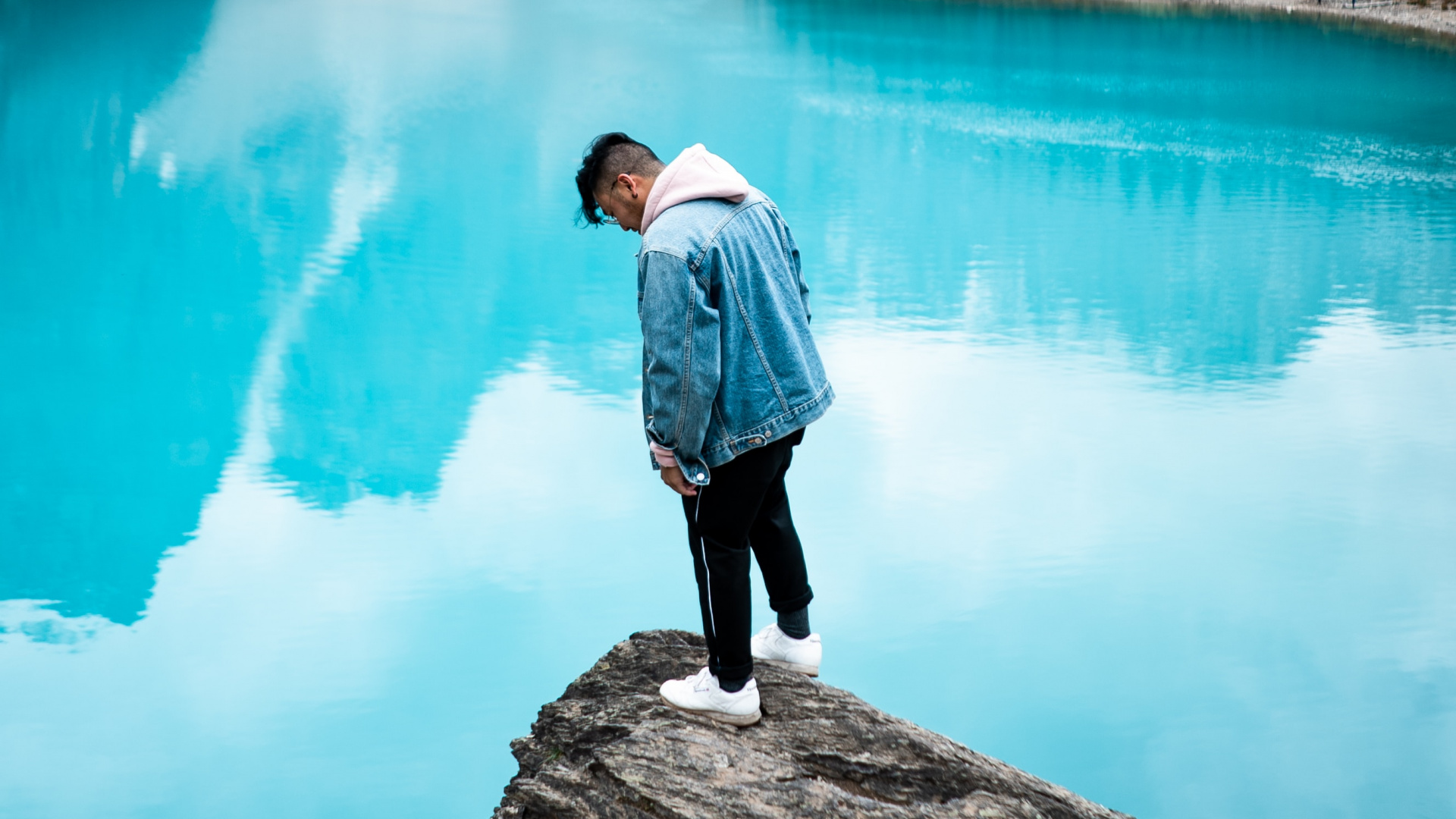 Man in White Dress Shirt Standing on Rock Near Lake During Daytime. Wallpaper in 1920x1080 Resolution
