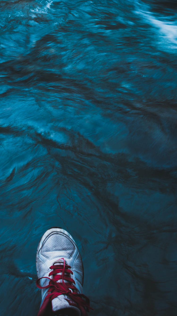 Persona en Zapatillas Blancas y Negras de Pie Sobre el Agua. Wallpaper in 750x1334 Resolution