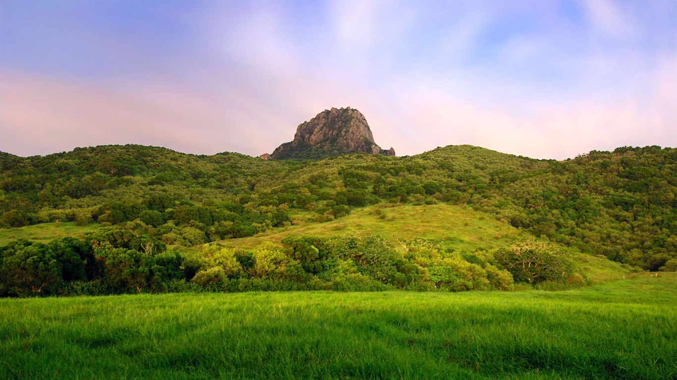 Green Grass Field Near Mountain Under Cloudy Sky During Daytime. Wallpaper in 1366x768 Resolution