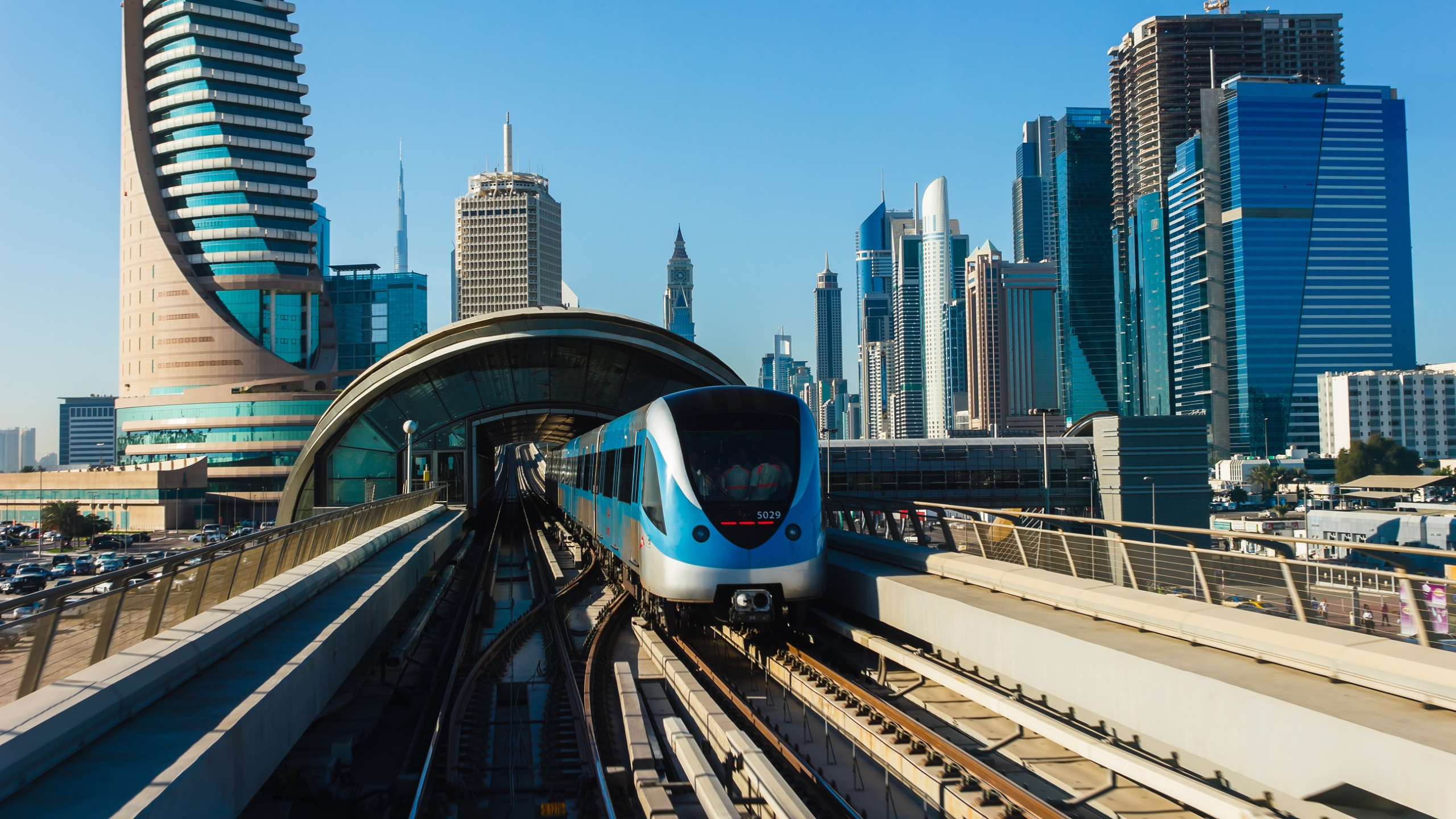 White and Blue Train on Rail Tracks Near City Buildings During Daytime. Wallpaper in 2560x1440 Resolution
