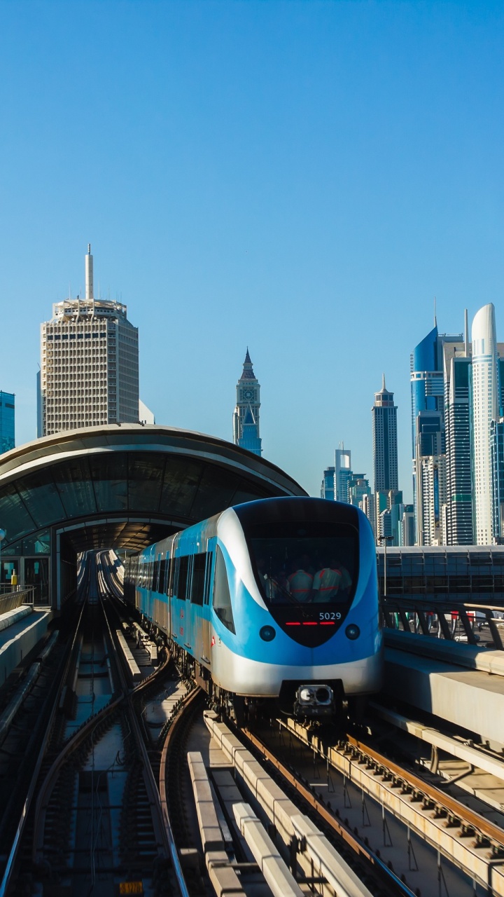 White and Blue Train on Rail Tracks Near City Buildings During Daytime. Wallpaper in 720x1280 Resolution