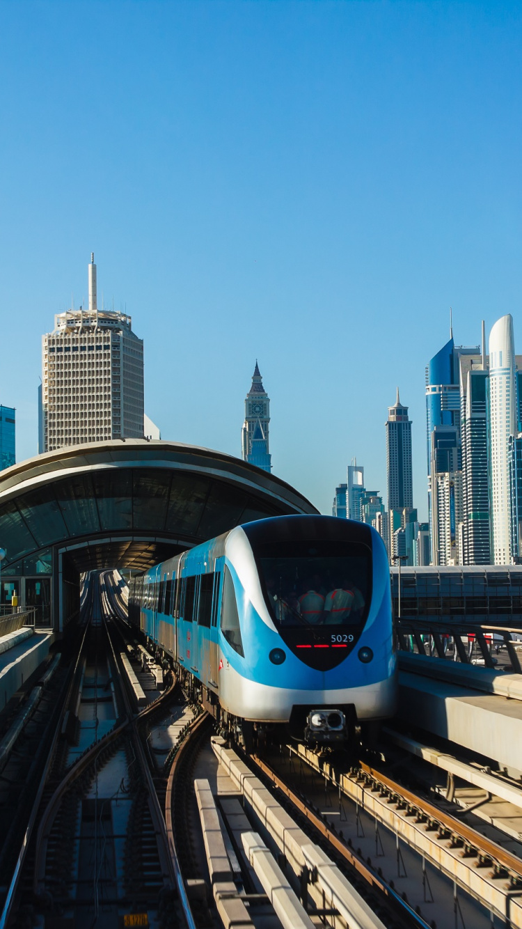 White and Blue Train on Rail Tracks Near City Buildings During Daytime. Wallpaper in 750x1334 Resolution