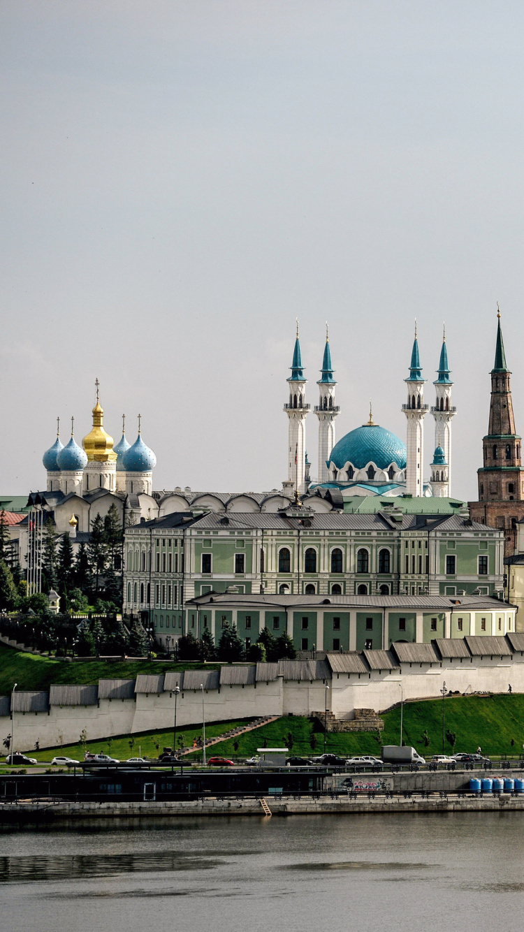 White and Green Concrete Building Near Body of Water During Daytime. Wallpaper in 750x1334 Resolution