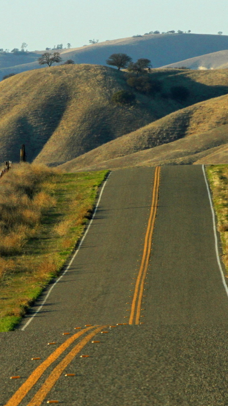 Gray Asphalt Road Between Green Grass Field During Daytime. Wallpaper in 750x1334 Resolution