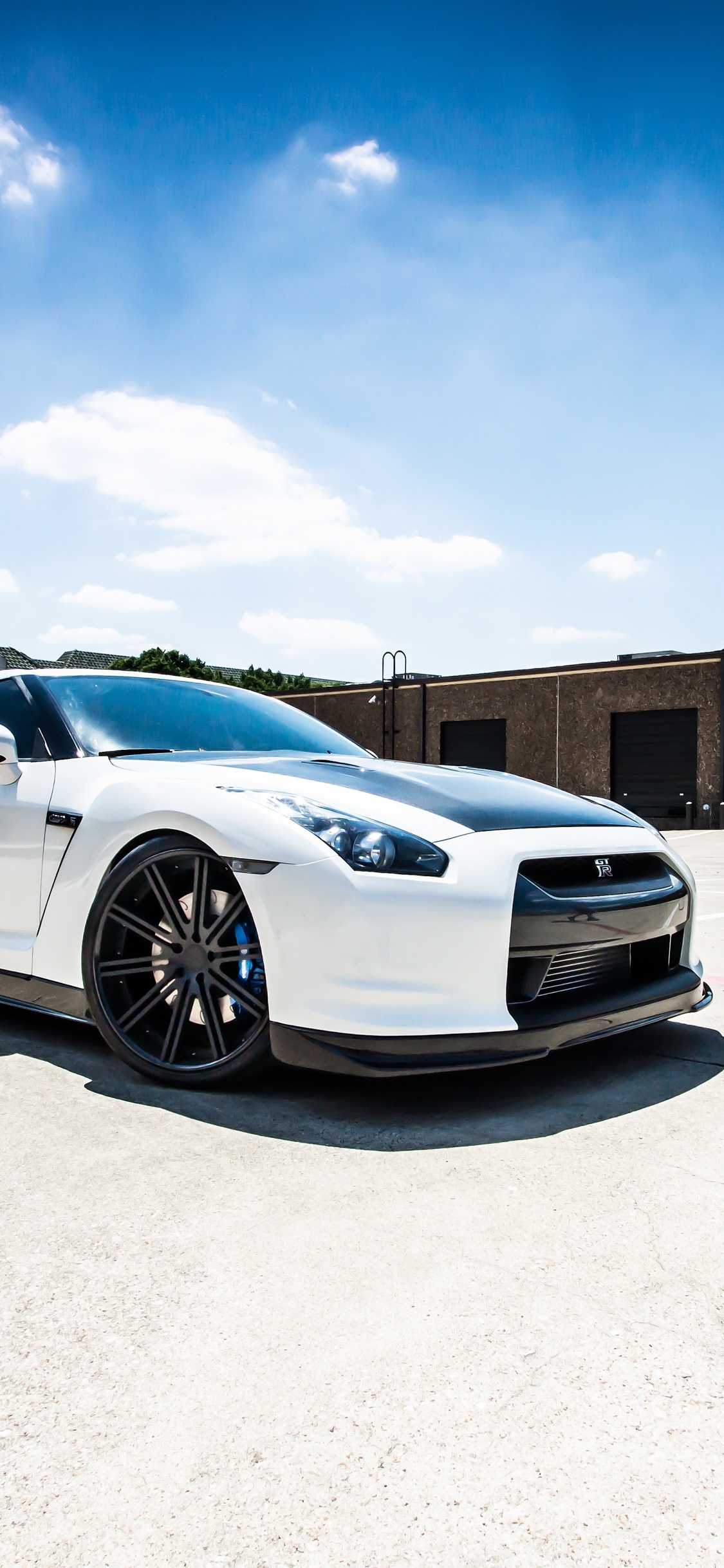 White Coupe Parked on Gray Concrete Floor During Daytime. Wallpaper in 1125x2436 Resolution