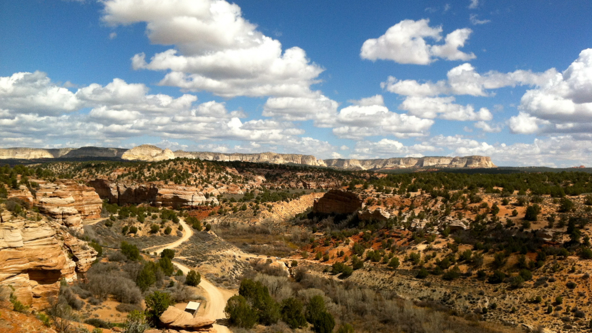 People Sitting on Brown Rock Formation Under Blue Sky and White Clouds During Daytime. Wallpaper in 1920x1080 Resolution