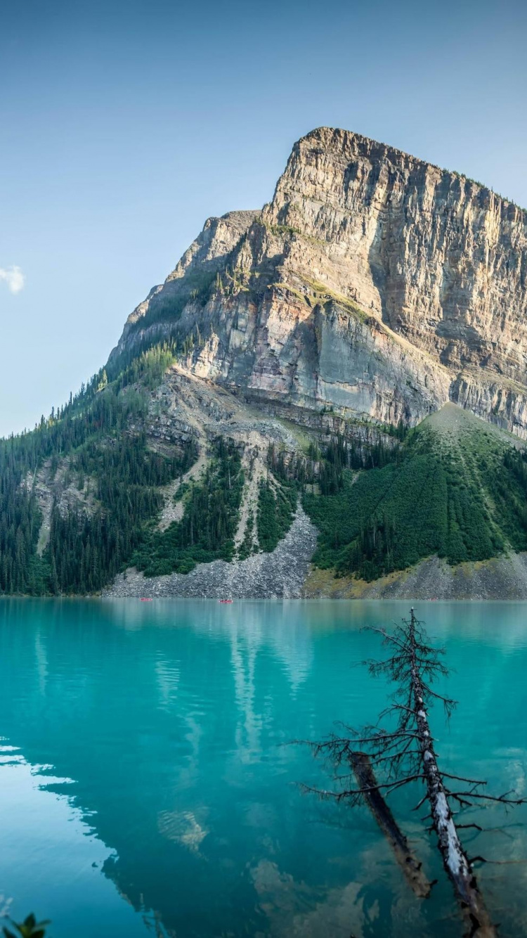Montagne Verte et Grise à Côté D'un Plan D'eau Sous un Ciel Bleu Pendant la Journée. Wallpaper in 750x1334 Resolution