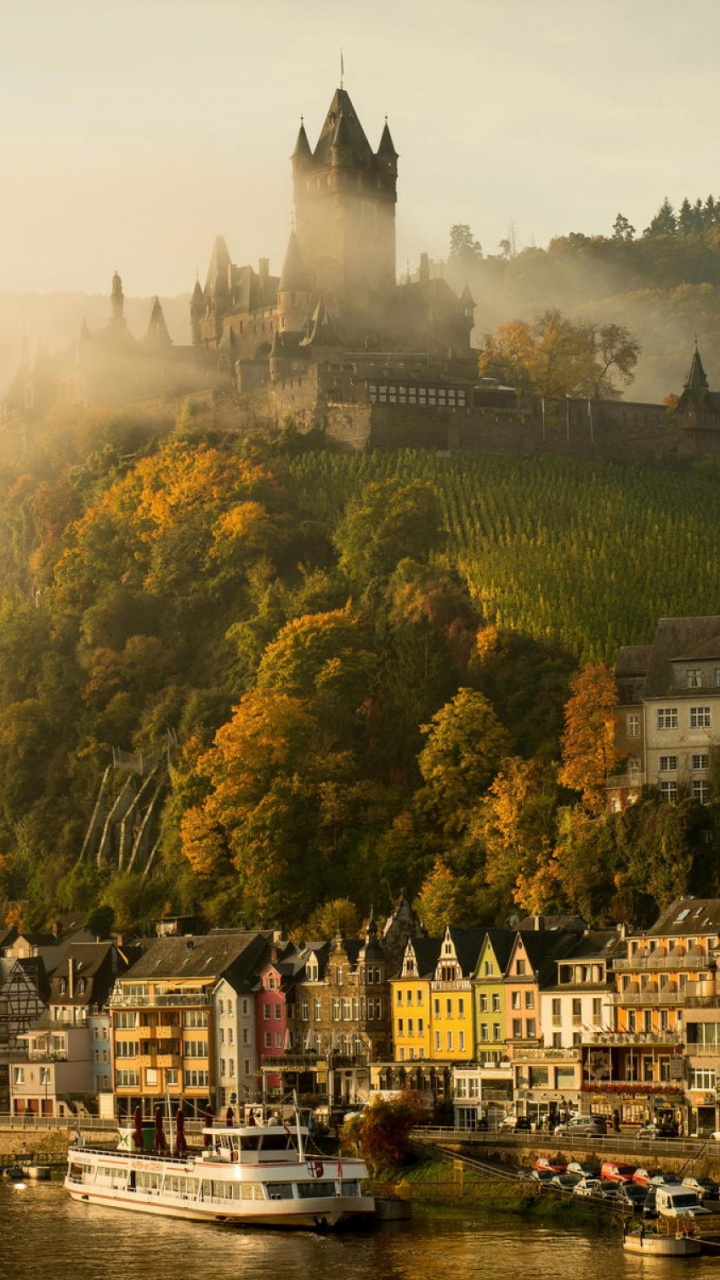 Weißes Und Braunes Betongebäude in Der Nähe Von Grünen Bäumen Und Gewässern Tagsüber. Wallpaper in 720x1280 Resolution