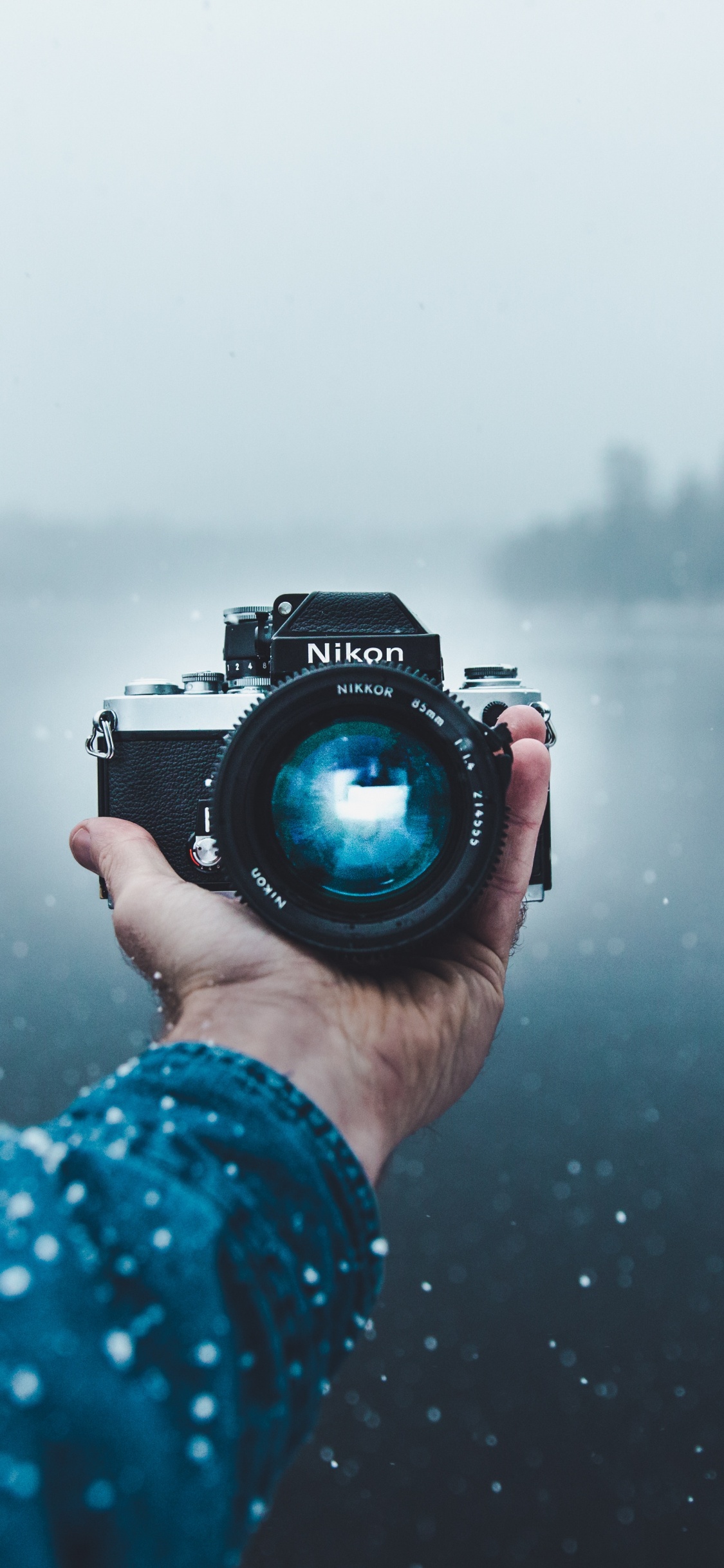 Person Mit Schwarzer DSLR-Kamera. Wallpaper in 1125x2436 Resolution