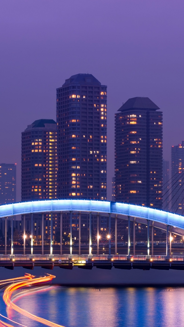 Lighted Bridge Over River Near High Rise Buildings During Night Time. Wallpaper in 720x1280 Resolution